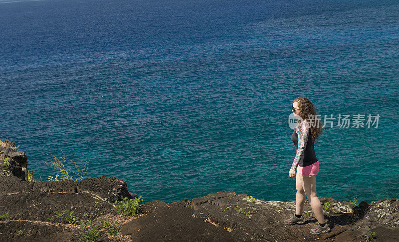 旅行中的美国女人沿着夏威夷海边的悬崖行走