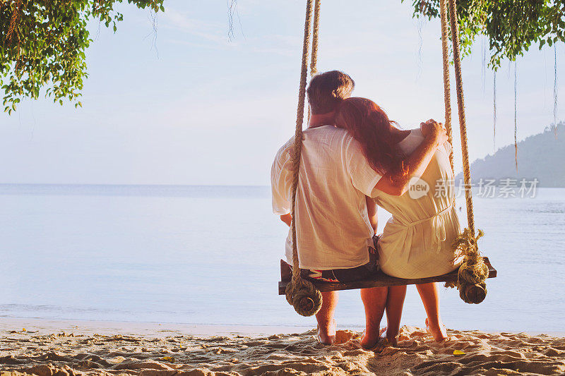 浪漫的假期，蜜月，深情的情侣在沙滩上荡秋千