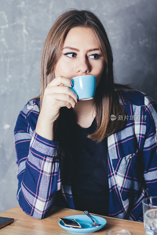 年轻的白人妇女捧着一杯咖啡享受在自由时间的肖像。