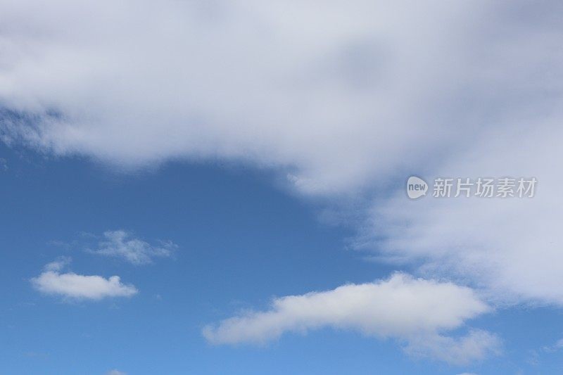 蓝色天空映衬着蓬松、缕缕白云的特写