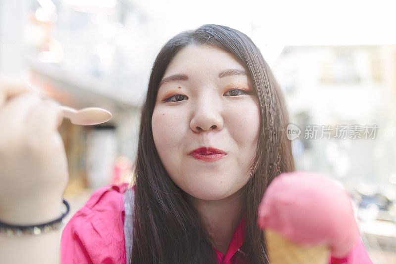 日本妇女愉快地吃着冰淇淋