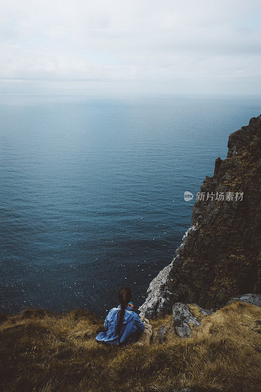 在挪威徒步旅行和看海后带着狗休息的女人