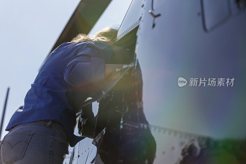年轻的女工程师正在仔细观察直升机的发动机舱