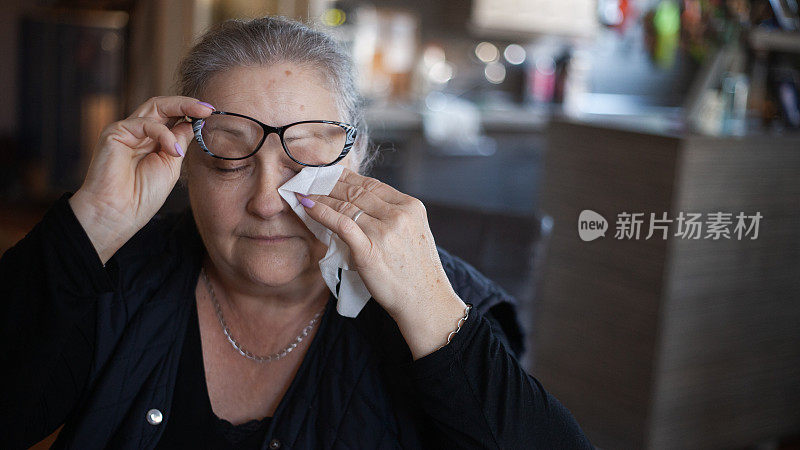 老年妇女过敏，用纸巾擤鼻子