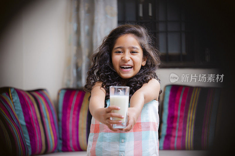 肖像一个开朗可爱的女孩微笑着拿着一杯牛奶的照片