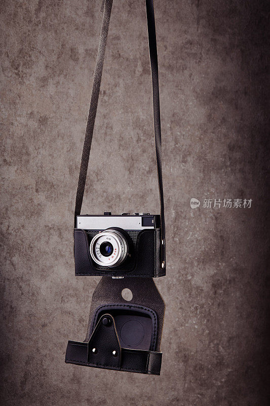 老式模拟测距胶片相机在皮箱挂在前面的混凝土纹理墙作为背景