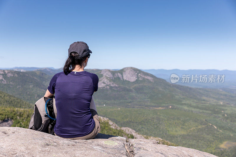 在加拿大魁北克省大花园国家公园徒步旅行后，一名妇女在山顶休息