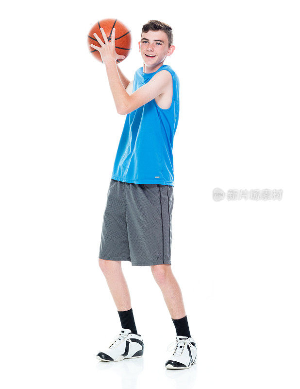 白人男孩篮球运动员站在白色背景和拿篮球和使用运动球