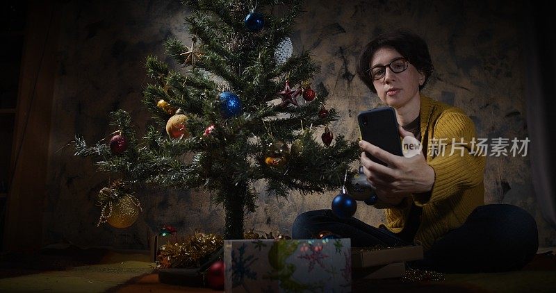 女人在家里装饰圣诞树和打电话