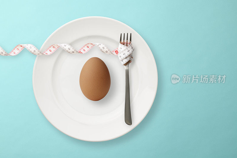 鸡蛋放在盘子里，用卷尺把叉子卷起来。