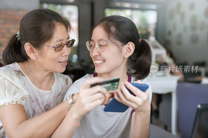 亚洲青少年使用妈妈的信用卡支付网上购物在咖啡馆