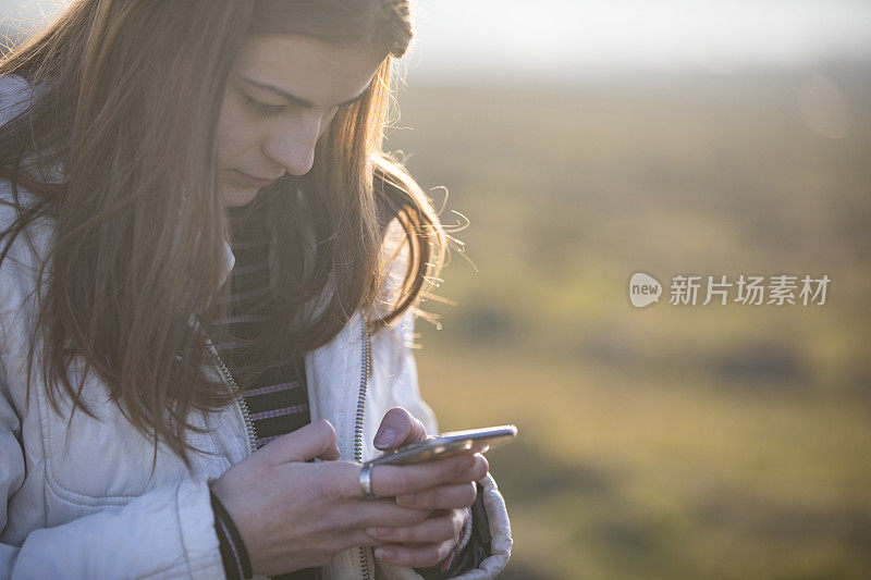 少女使用手机在户外的农村场景