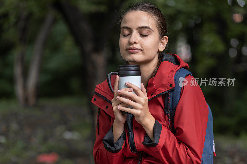 穿着红色雨衣的年轻女子在大自然中徒步旅行