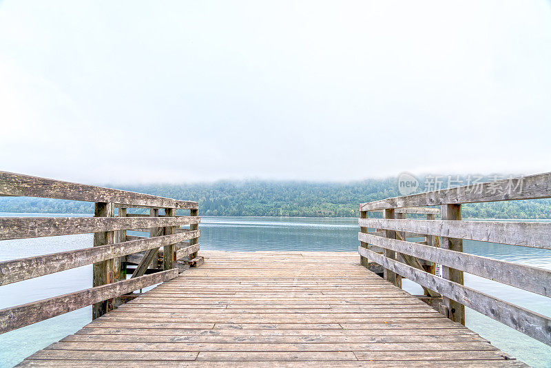 在朱利安阿尔卑斯的博欣湖的雾晨木制码头