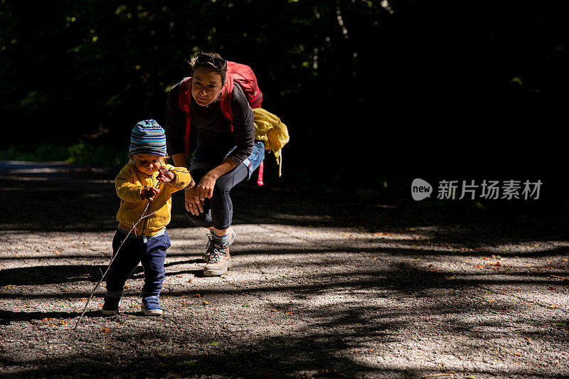 年轻的母亲和她蹒跚学步的孩子在当地的山上探险