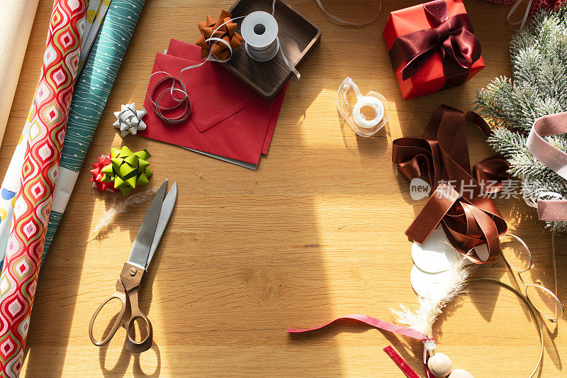 包装圣诞礼物:一个凌乱的桌面组成的各种装饰项目:包装纸，丝带，礼品盒，圣诞卡