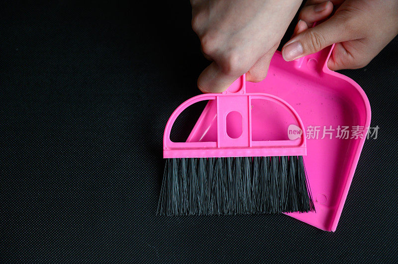 用粉红色的扫帚和簸箕扫地