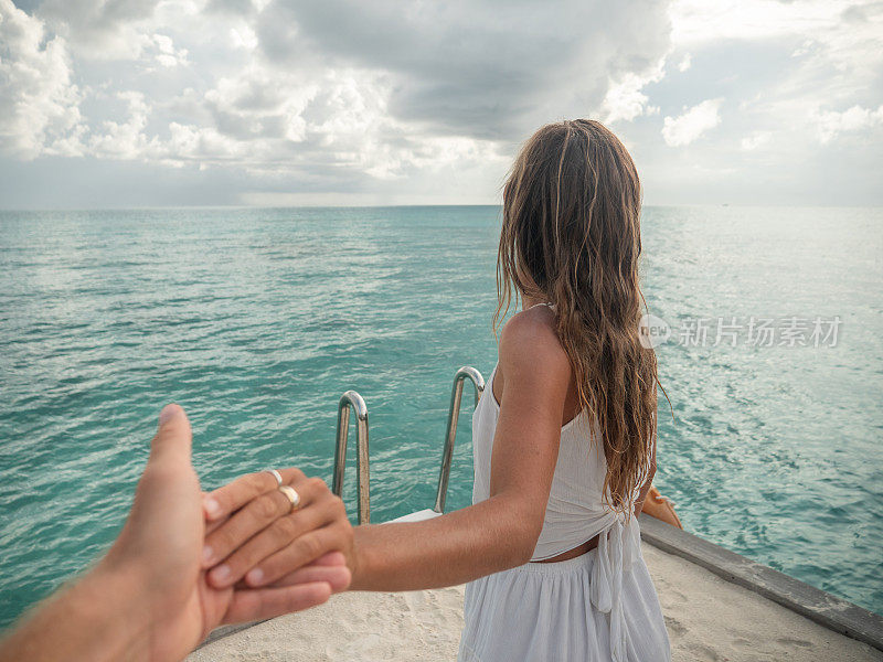 在马尔代夫，一对夫妇手牵着手，女人领着路来到户外露台