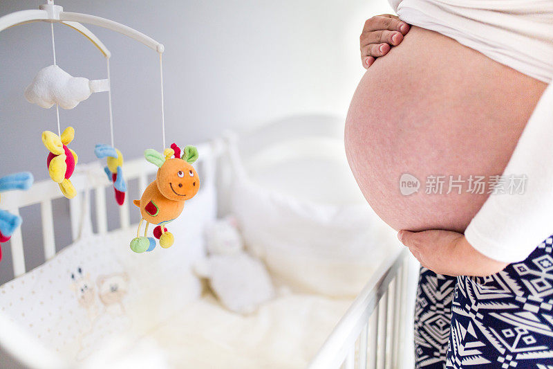 孕妇站在婴儿床旁摸肚子