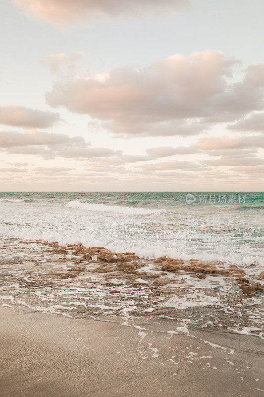 彩色天空在一个岩石海滩日落在木星，佛罗里达州在2021年3月