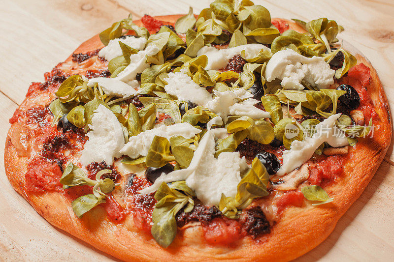 披萨与马苏里拉奶酪，意大利腊肠，番茄酱，胡椒，香料和新鲜芝麻菜库存照片
