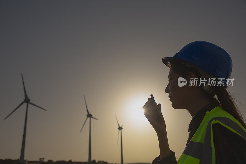 日落时分，年轻的维护工程师在风力涡轮机农场工作。