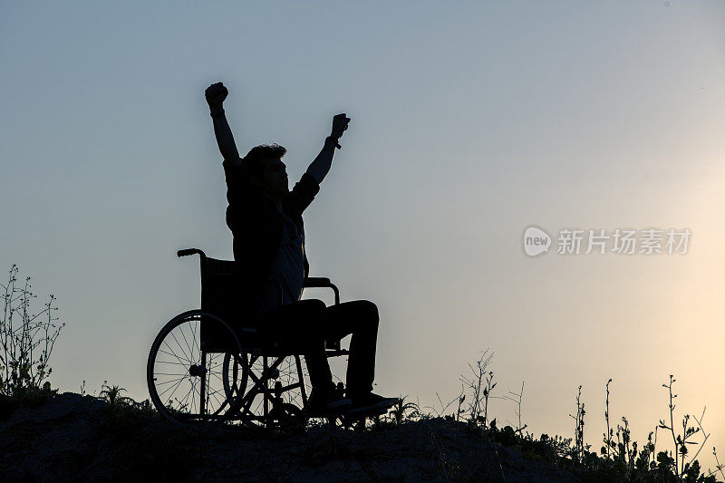 残疾人有希望。他坐在轮椅上，在日落时伸出双手