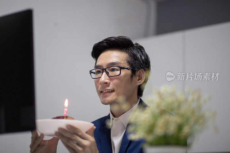亚洲华人男子在家庭办公室庆祝他的生日，与他的同事在其他分公司视频会议
