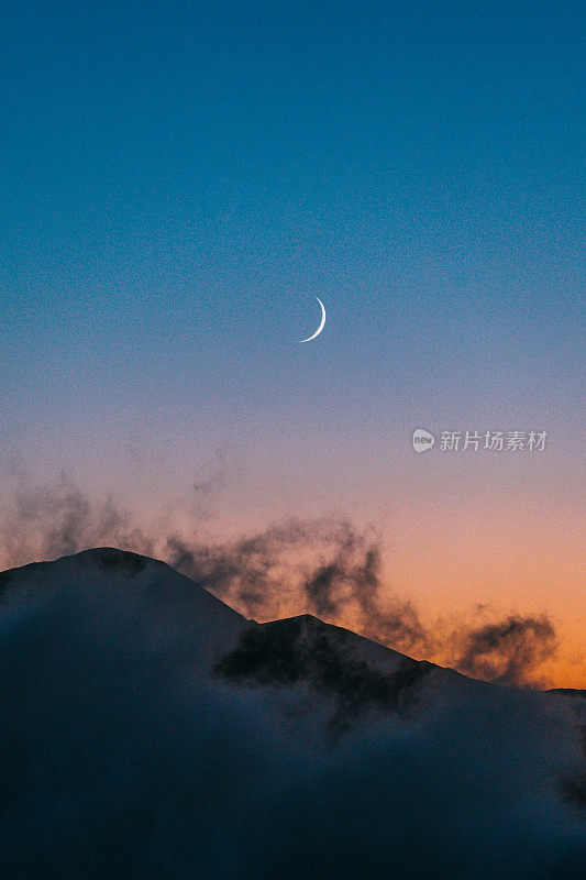 壮丽的风景与塔特拉山后日落。山峰的轮廓映衬着蓝色和粉色的天空、浮云和月亮
