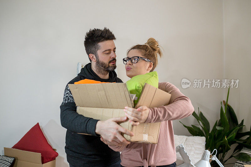 一对漂亮的年轻夫妇在搬到新家的时候，手里拿着纸板箱