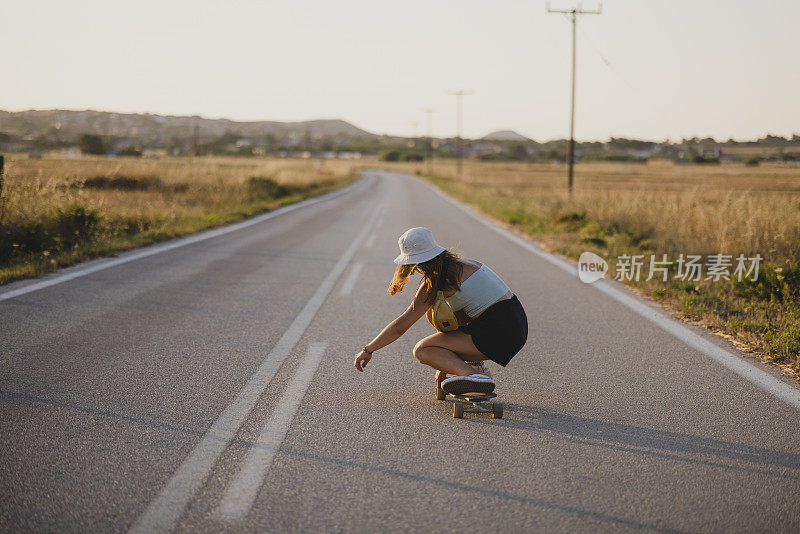 年轻的白人女子在路上骑着她的长板