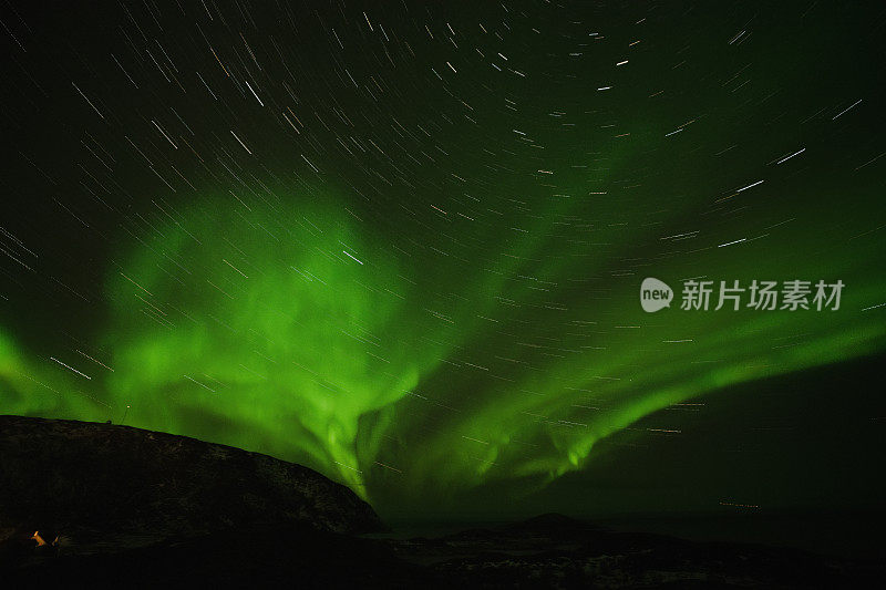 绿色的北极光在夜空和星星的轨迹