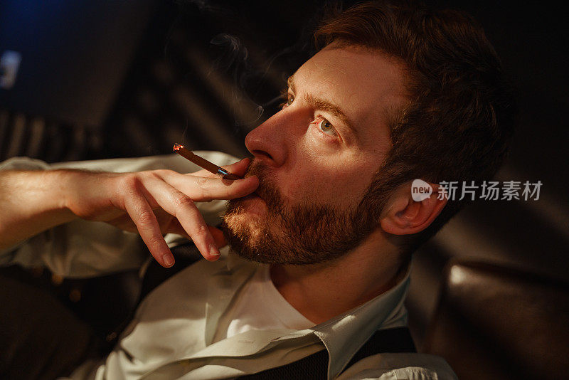 一个留着胡子抽烟的男人的大气肖像。