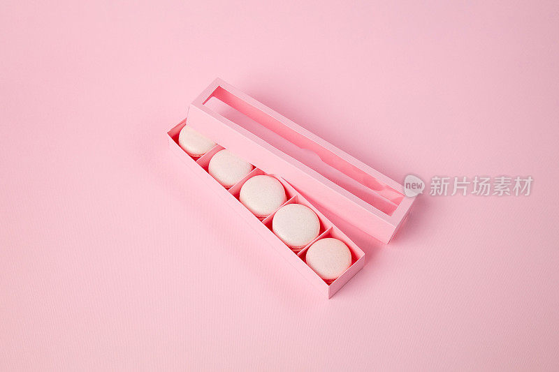 粉色马卡龙排列在粉红色的开放倾斜矩形盒中