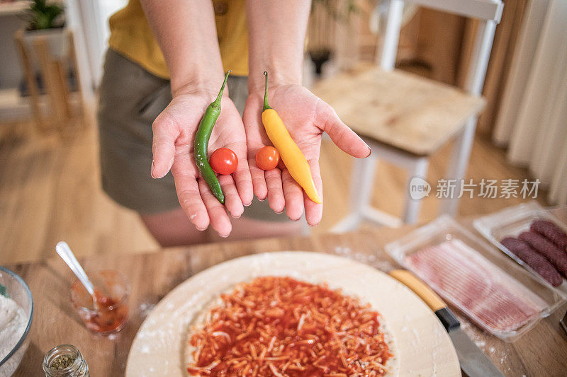 一位年轻女子正在家里准备披萨。网上食谱和食物准备。