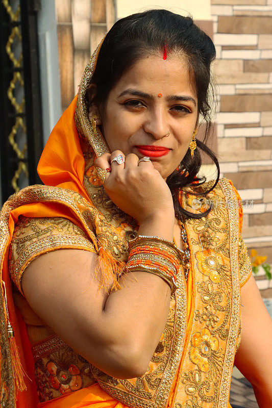 印度教徒的特写图像，穿着传统服装的印度妇女，橙色，绣花纱丽，穿着sindoor在头发分开，bindi在前额，头部特写，看着相机，聚焦在前景