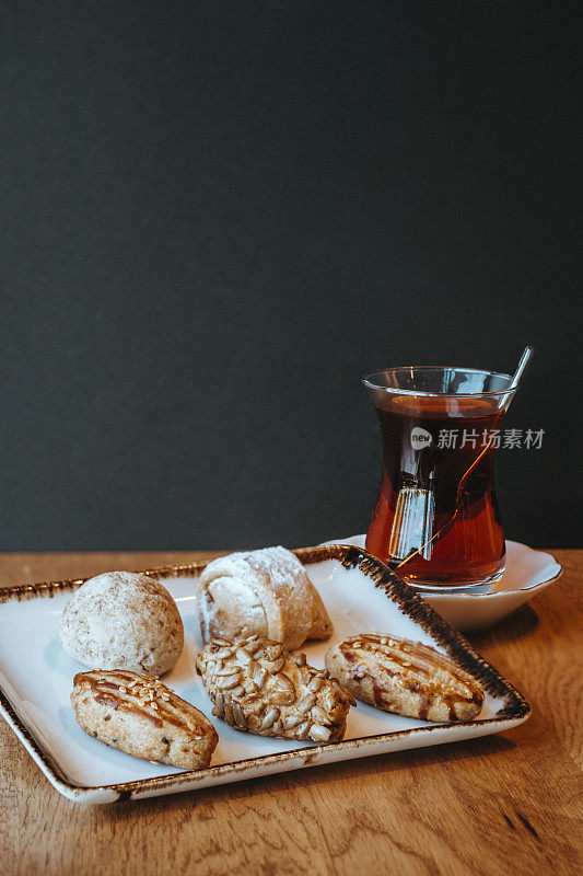 什锦或混合饼干，迷你马卡龙和彩色马卡龙，红茶(土耳其茶)，木桌上的饼干和茶，迷你acibadem饼干，咸和糖饼干
