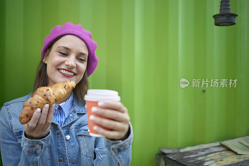 女人咬牛角面包户外酒吧早餐