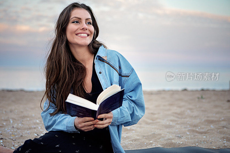 年轻女子在海滩上看书的肖像