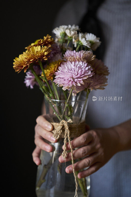 女孩正在玻璃花瓶里插花