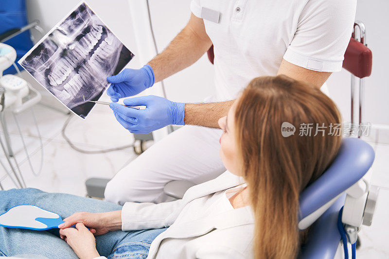 牙科医生在诊所向妇女展示牙科x光扫描图