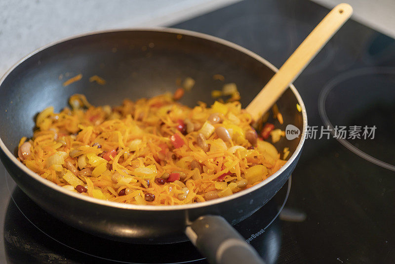 在现代厨房的电磁炉上烹饪素食玉米卷饼。