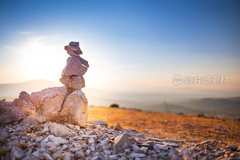 石头堆叠与平衡的石头在模糊的山背景在日落温暖的光股票照片