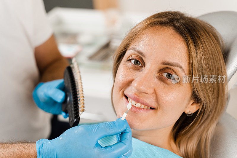 牙齿颜色深浅引导与女性患者的特写。牙齿美白。在牙科诊所处理牙齿颜色匹配样本的牙医。牙医。