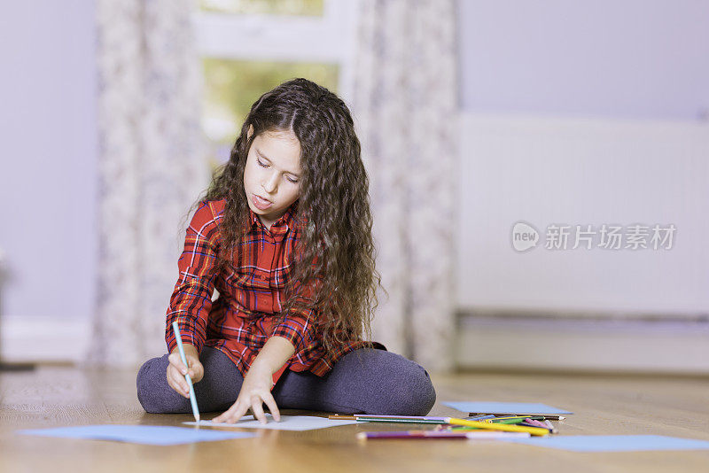 小女孩在地板上画蜡笔