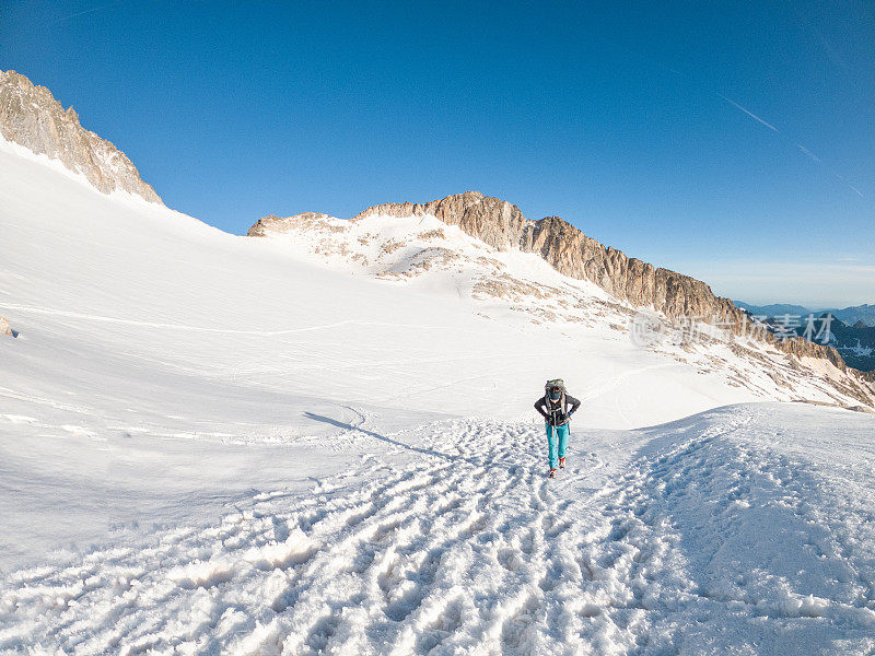 女登山者在雪道上攀登山峰