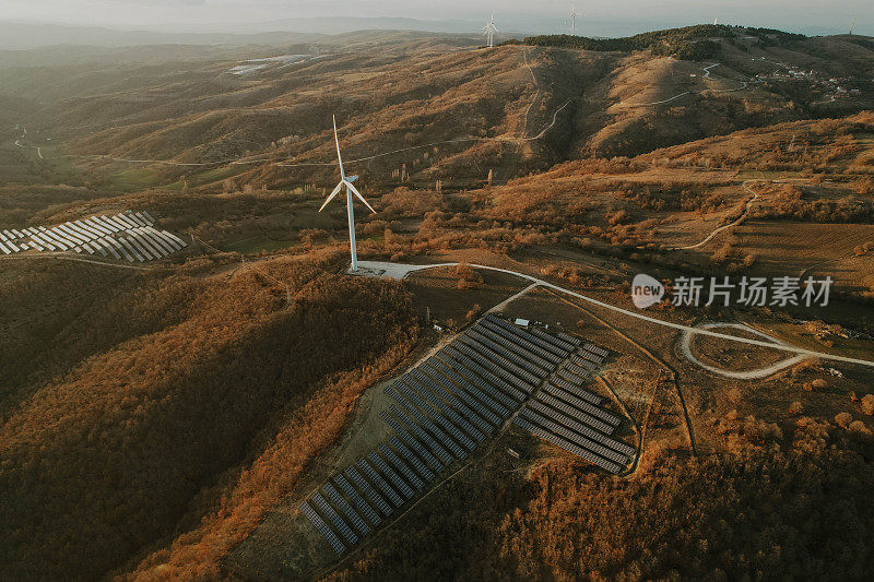 日落时的太阳能电池板和风力涡轮机。可再生能源