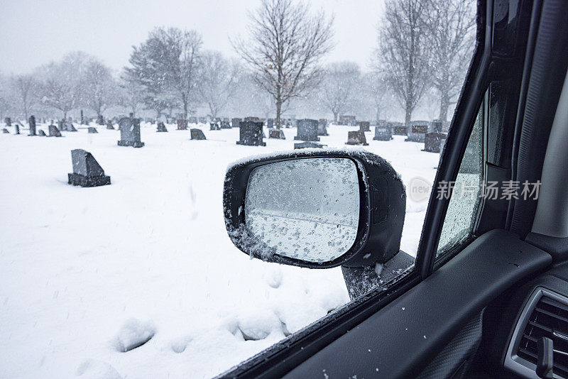 从打开的车窗看冬季暴风雪的乡村墓地