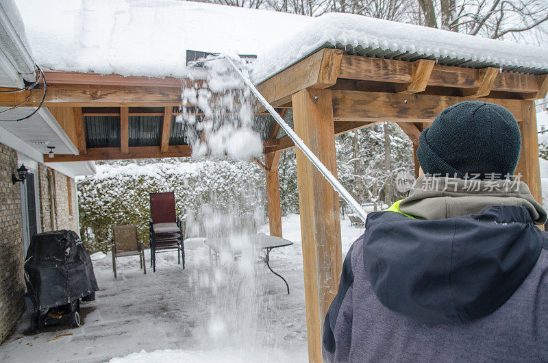 十几岁的男孩正在清除天井屋顶上的积雪