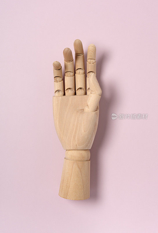 木制人体模型的手放在粉红色的背景。